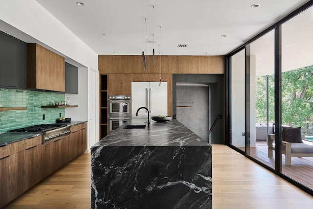 3003 Oakhaven Dr, Austin, TX 78704 - kitchen featuring stainless steel appliances, modern cabinets, decorative backsplash, light wood finished floors, and a wall of windows