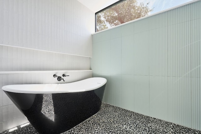 bathroom with a bathtub and tile walls