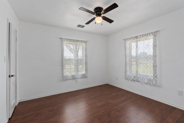 empty room featuring a healthy amount of sunlight, dark hardwood / wood-style floors, and ceiling fan