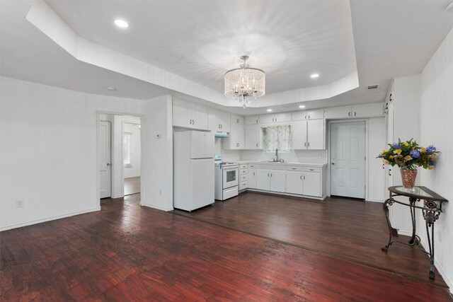 kitchen with sink, white appliances, dark wood-type flooring, white cabinets, and a raised ceiling