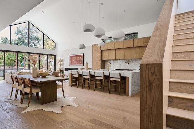 dining area with light hardwood / wood-style floors, sink, and a high ceiling