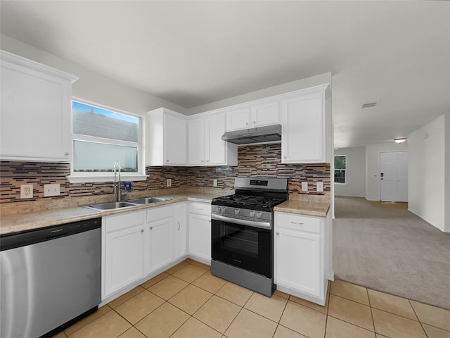 kitchen featuring stainless steel appliances, sink, backsplash, light colored carpet, and white cabinetry