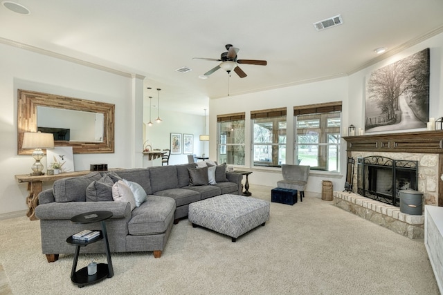 carpeted living room featuring ornamental molding, a stone fireplace, and ceiling fan