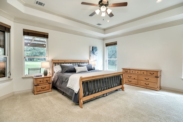 bedroom with ceiling fan, light carpet, multiple windows, and a tray ceiling