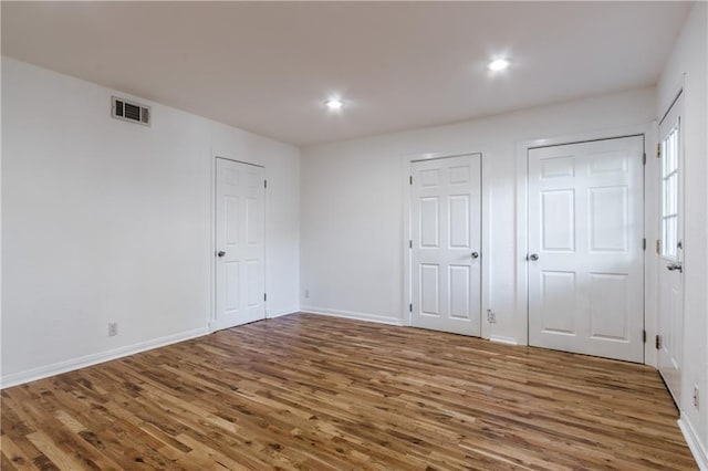 unfurnished bedroom featuring recessed lighting, visible vents, baseboards, and wood finished floors