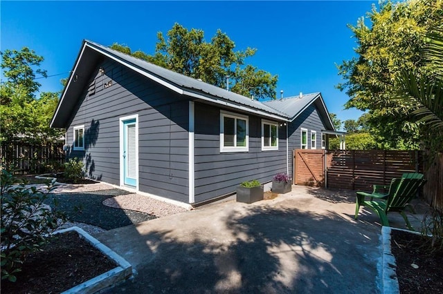 view of home's exterior featuring metal roof, a patio area, and fence