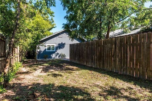 view of side of home featuring a fenced backyard and a lawn