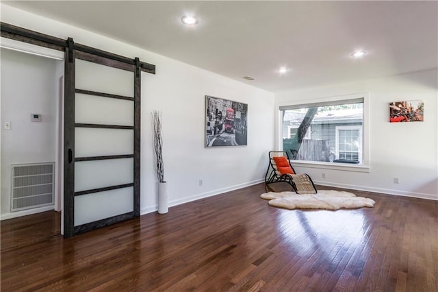 sitting room with a barn door, recessed lighting, dark wood-style flooring, visible vents, and baseboards