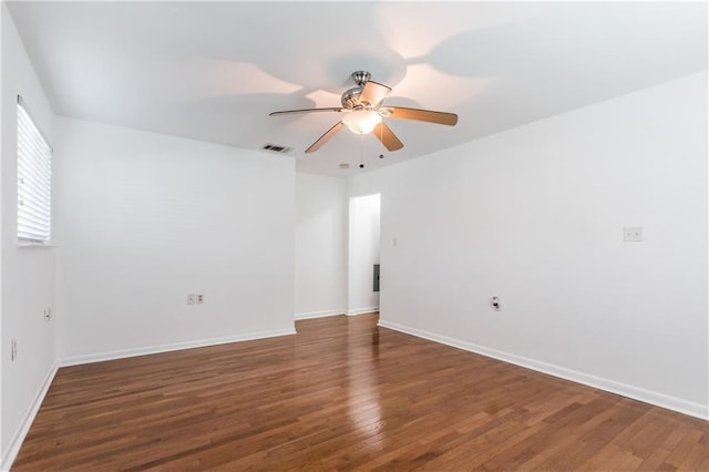 spare room with baseboards, visible vents, dark wood finished floors, and a ceiling fan