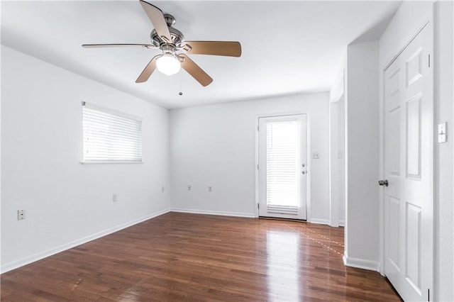 empty room featuring dark wood-type flooring, baseboards, and a ceiling fan