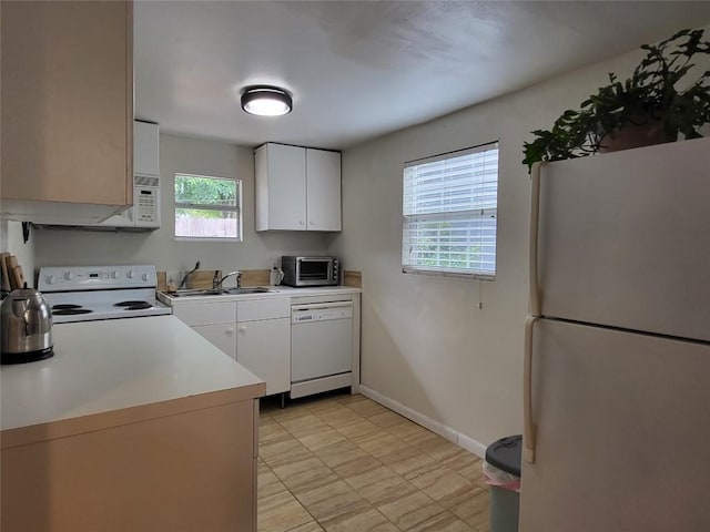 kitchen with white appliances, a sink, white cabinetry, baseboards, and light countertops