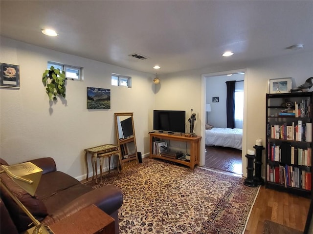 living area with recessed lighting, visible vents, baseboards, and wood finished floors