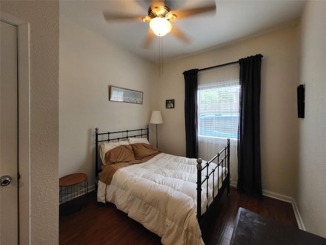 bedroom featuring ceiling fan, dark wood-style flooring, and baseboards