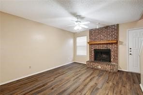 unfurnished living room featuring ceiling fan, brick wall, a brick fireplace, and wood-type flooring