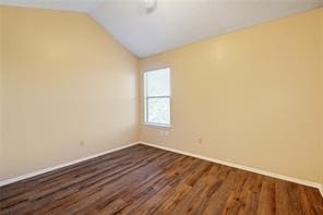 spare room featuring wood-type flooring and lofted ceiling