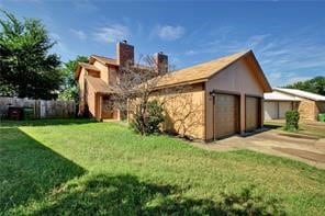 exterior space with a garage and a lawn