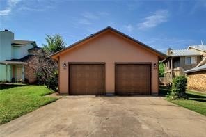 view of front of house with a garage, a front lawn, an outdoor structure, and stucco siding