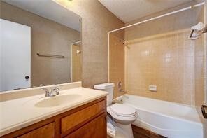 full bathroom with vanity, tiled shower / bath combo, and toilet