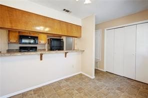 kitchen featuring range, a breakfast bar area, fridge, and light tile patterned floors