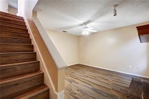 stairway featuring ceiling fan, wood-type flooring, and a textured ceiling