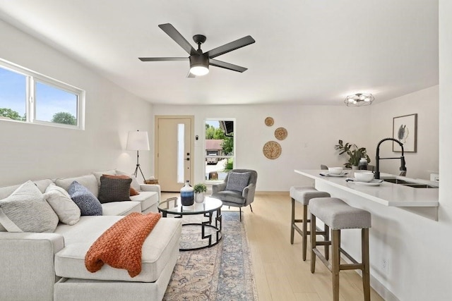 living room with sink, ceiling fan, and light wood-type flooring