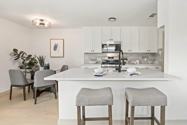 kitchen with a kitchen bar, white cabinetry, light hardwood / wood-style floors, and gas range