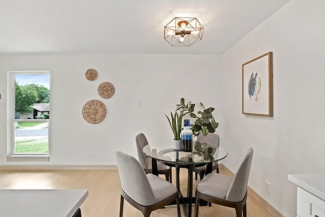 dining space with light hardwood / wood-style flooring and a chandelier