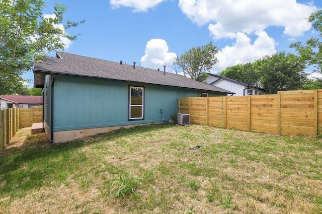 back of property featuring central air condition unit and a yard