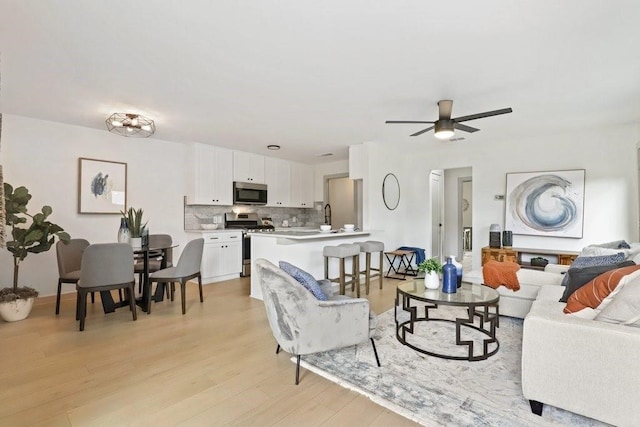 living room with ceiling fan and light wood-type flooring