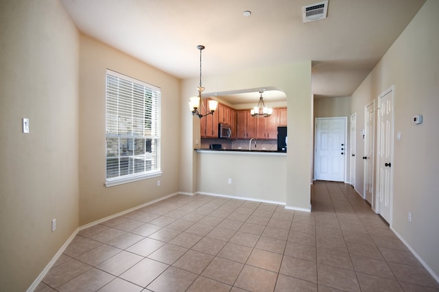 kitchen with a chandelier, backsplash, a healthy amount of sunlight, and light tile patterned floors