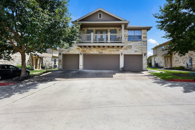 view of front of house featuring a balcony, a garage, and central air condition unit