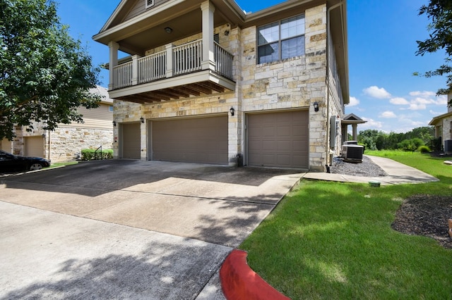 view of front facade with a balcony, a garage, central AC, and a front yard