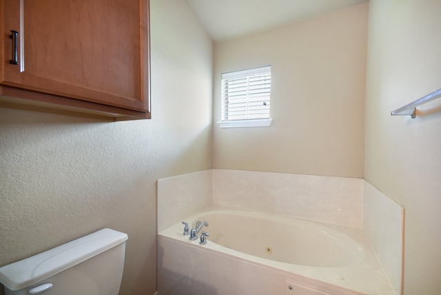 bathroom with a tub to relax in and toilet