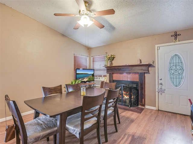 dining space featuring ceiling fan, a fireplace, hardwood / wood-style floors, and a textured ceiling