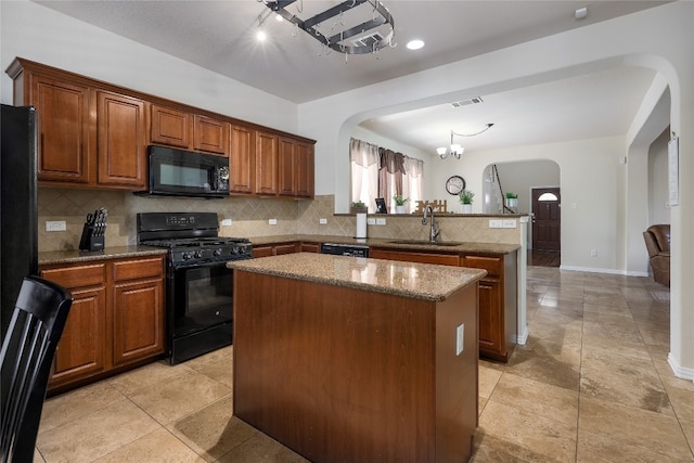 kitchen with sink, black appliances, tasteful backsplash, and a kitchen island