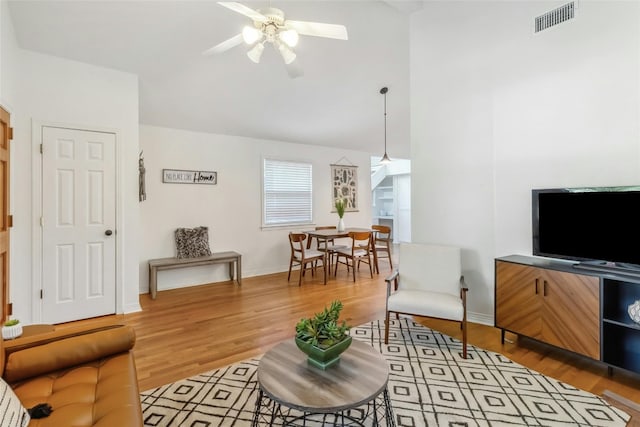 living room featuring light wood-type flooring, ceiling fan, and vaulted ceiling