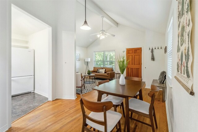 dining space with high vaulted ceiling, ceiling fan, light hardwood / wood-style floors, and beam ceiling