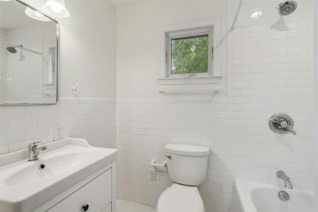 full bathroom with tile walls, backsplash, tiled shower / bath, toilet, and vanity