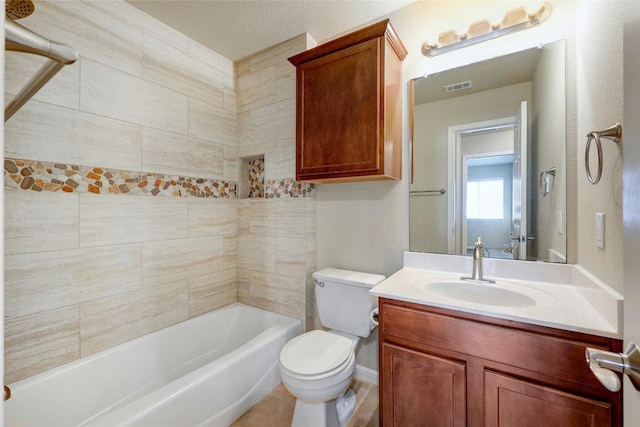 full bathroom featuring a textured ceiling, tiled shower / bath, toilet, vanity, and tile patterned floors