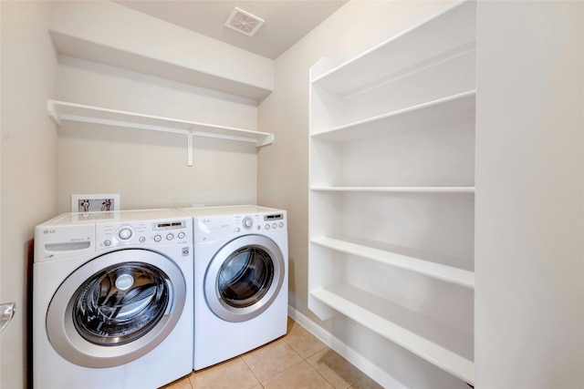 laundry area featuring washer and clothes dryer and light tile patterned floors