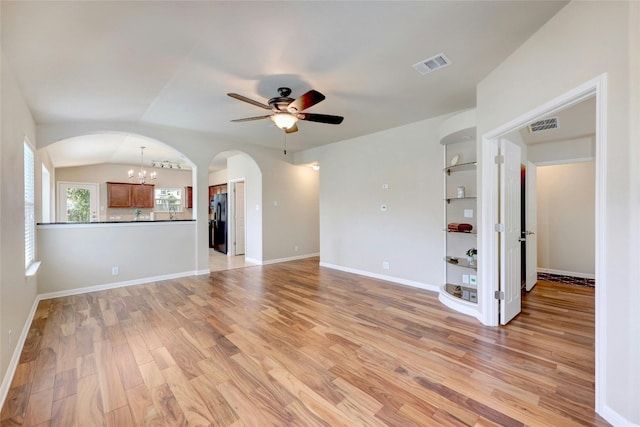 unfurnished living room featuring light wood-type flooring, ceiling fan with notable chandelier, and vaulted ceiling