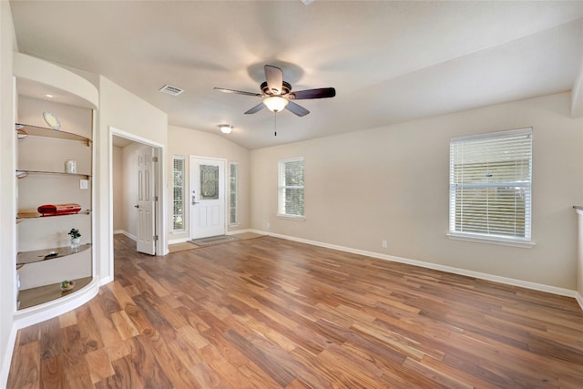 unfurnished living room featuring lofted ceiling, built in shelves, hardwood / wood-style floors, and ceiling fan