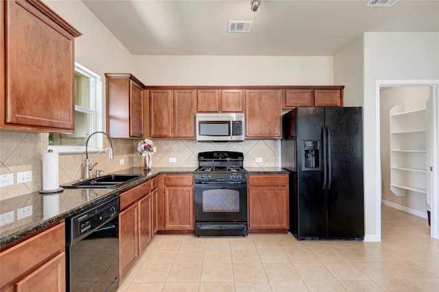 kitchen featuring dark stone counters, black appliances, decorative backsplash, sink, and light tile patterned floors