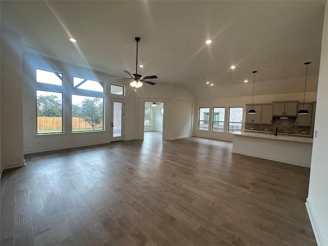 unfurnished living room with ceiling fan, dark hardwood / wood-style floors, sink, and high vaulted ceiling