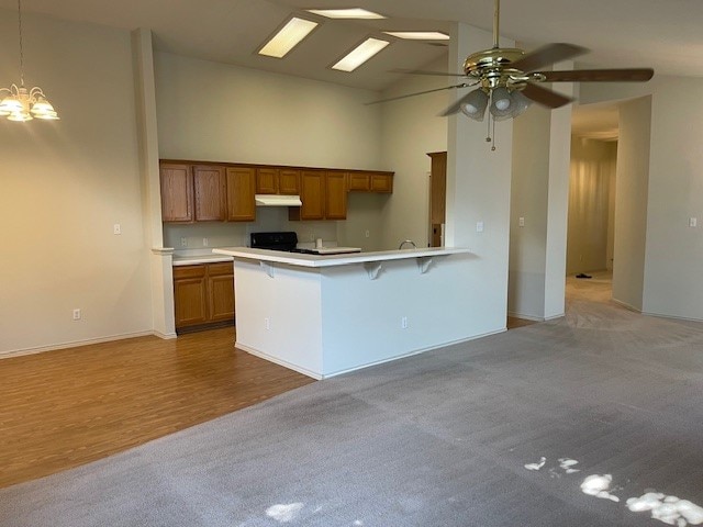 kitchen featuring ceiling fan with notable chandelier, light colored carpet, and high vaulted ceiling