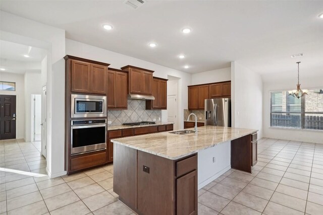 kitchen featuring tasteful backsplash, stainless steel appliances, sink, a center island with sink, and light tile patterned floors