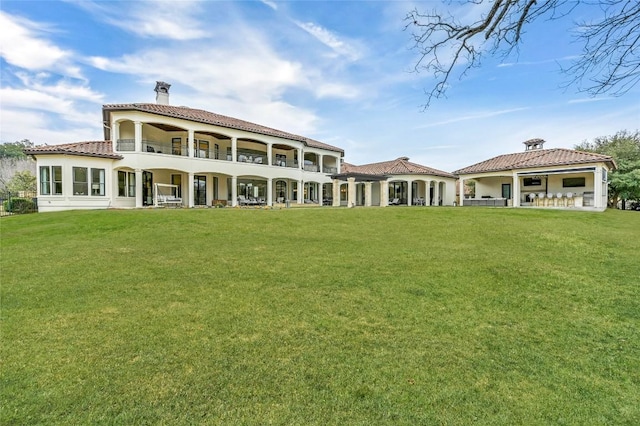 rear view of property with a balcony and a yard