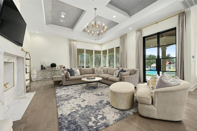 living room with beam ceiling, coffered ceiling, a chandelier, and light hardwood / wood-style flooring