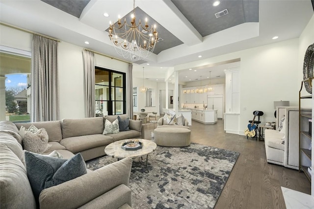 living room with a tray ceiling, dark hardwood / wood-style floors, and a chandelier