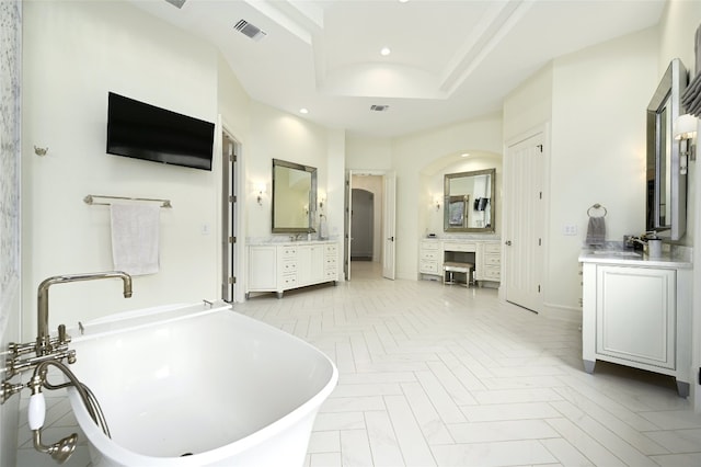 bathroom with a raised ceiling, vanity, a tub, and parquet floors